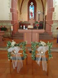 Zwei blumengeschmückte Stühle für das Brautpaar stehen vor dem Altar